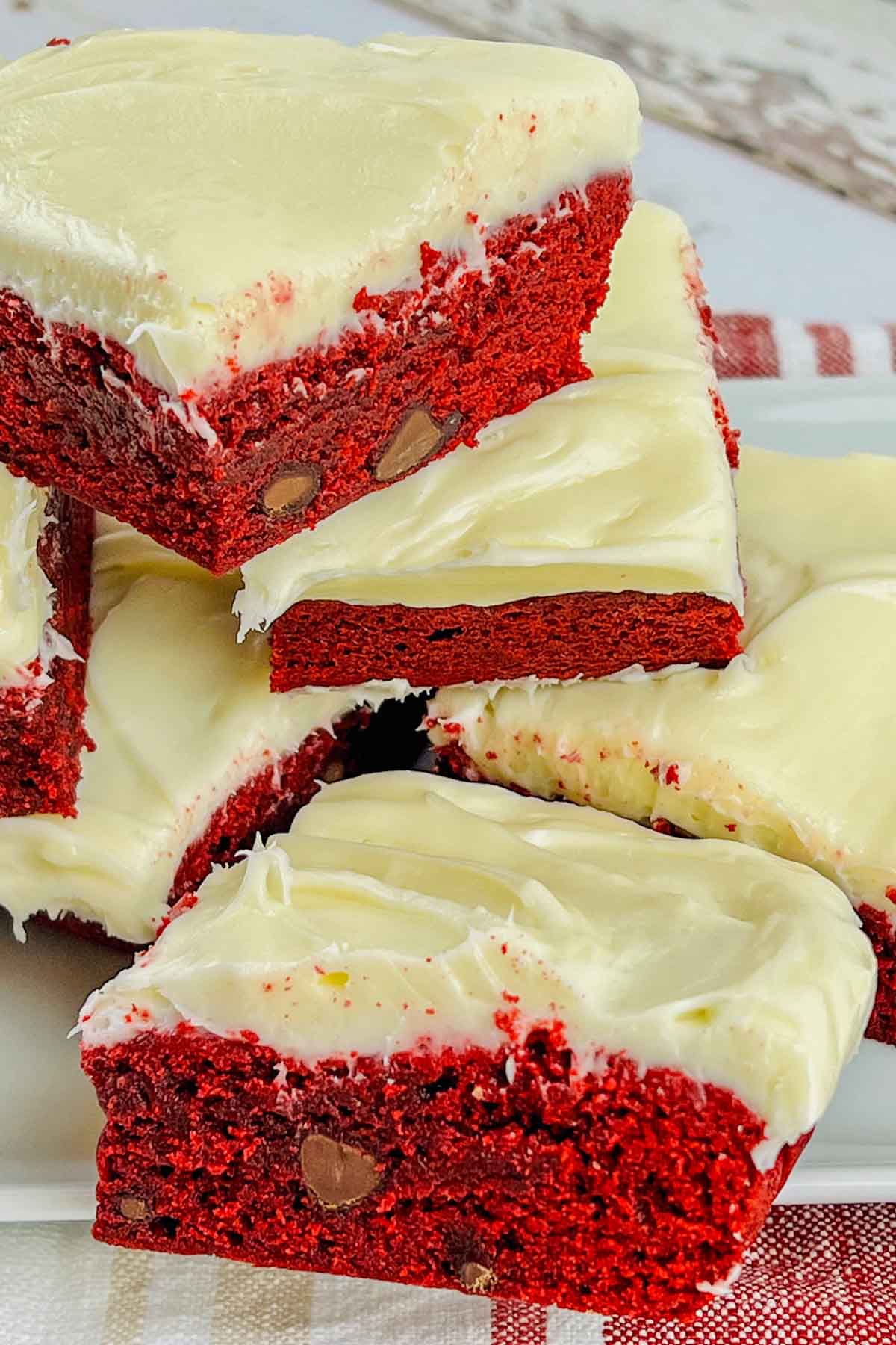 red velvet brownies topped with frosting and stacked.