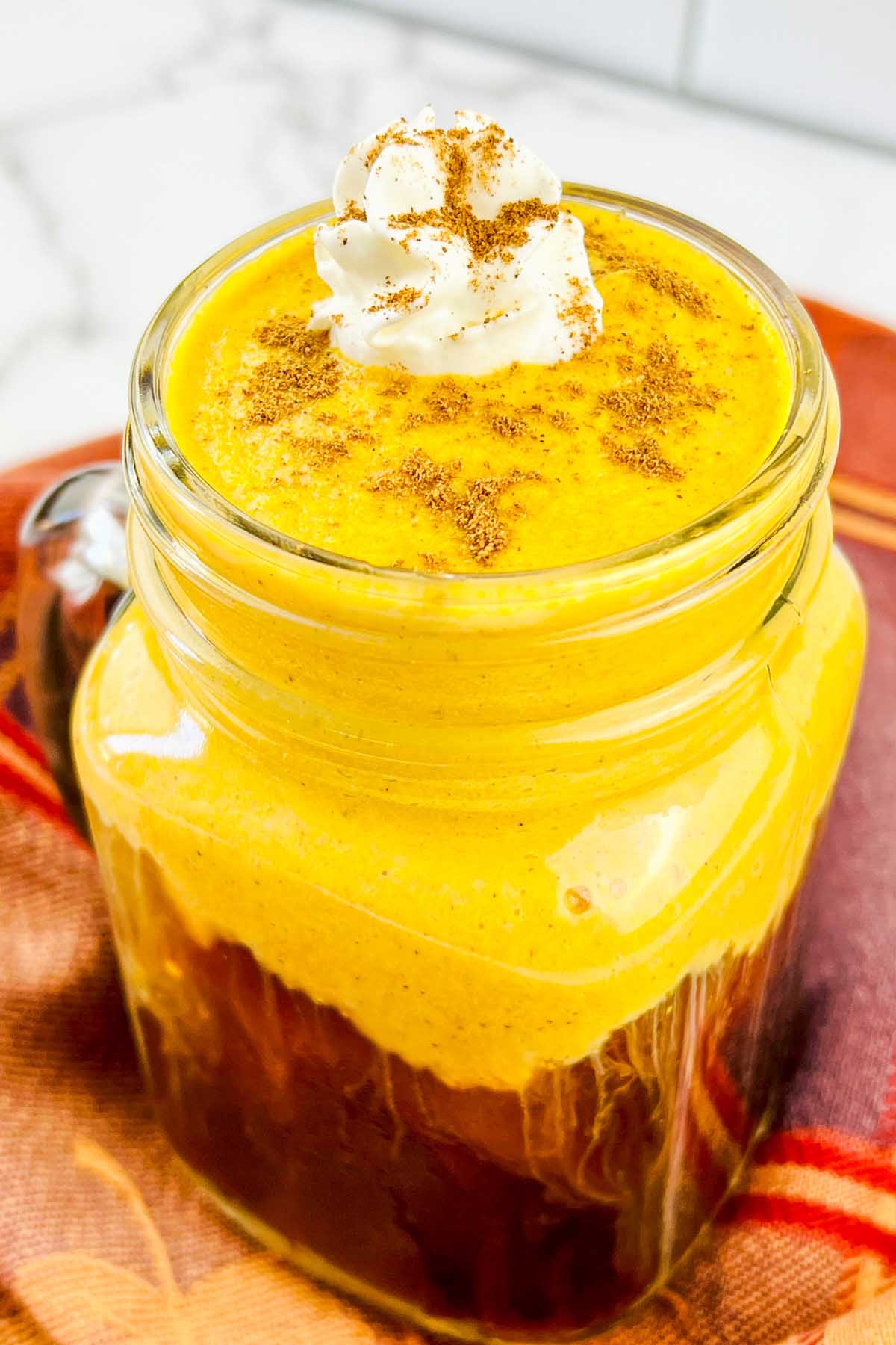 Pumpkin foam in a glass with whipped cream on top.