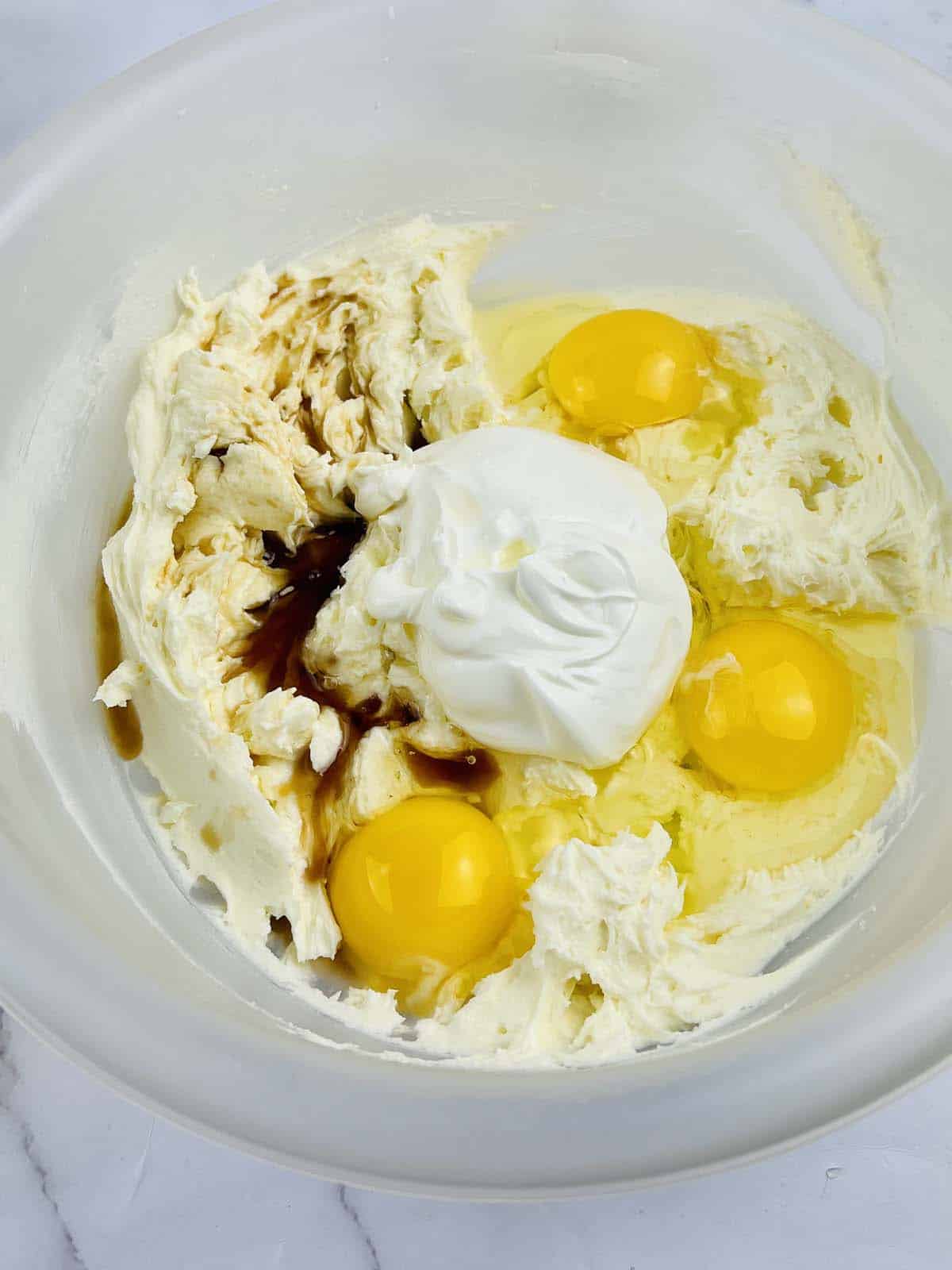 Sour cream, vanilla and eggs added to bowl.