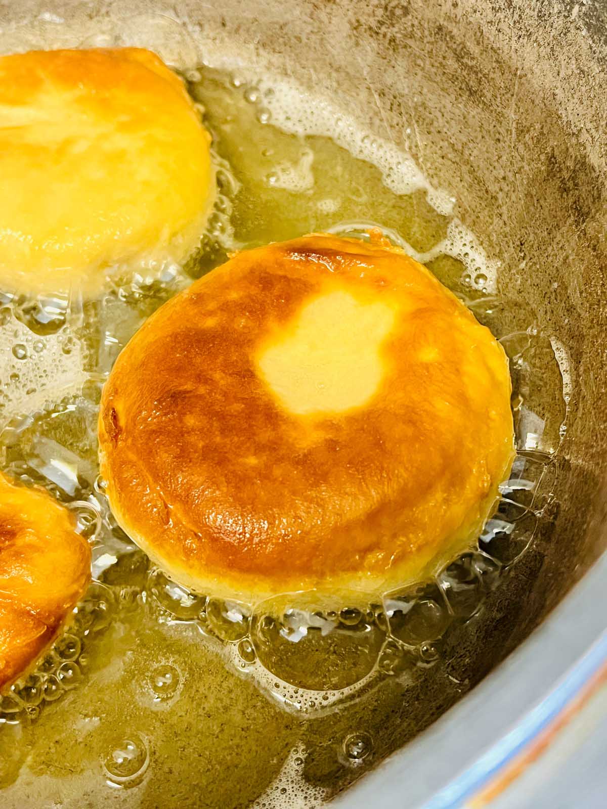 Cooked donut in a frying pan.