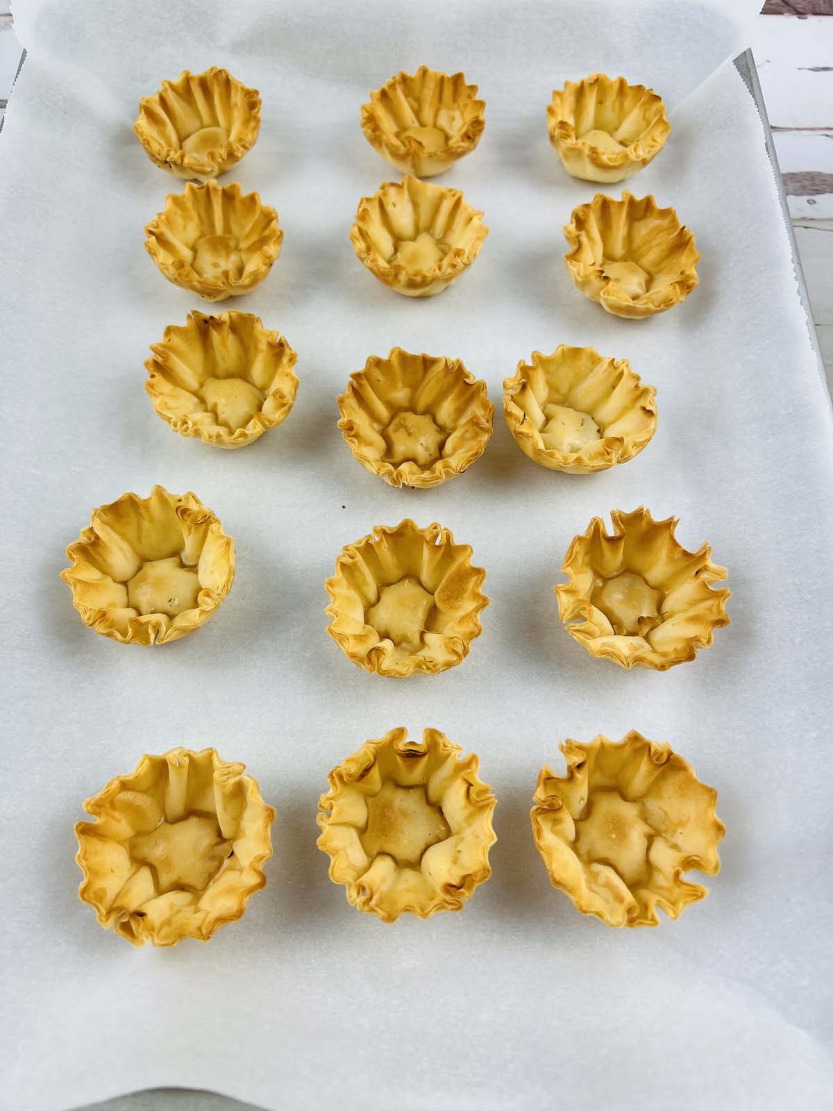 Baked phyllo shells on parchment paper.