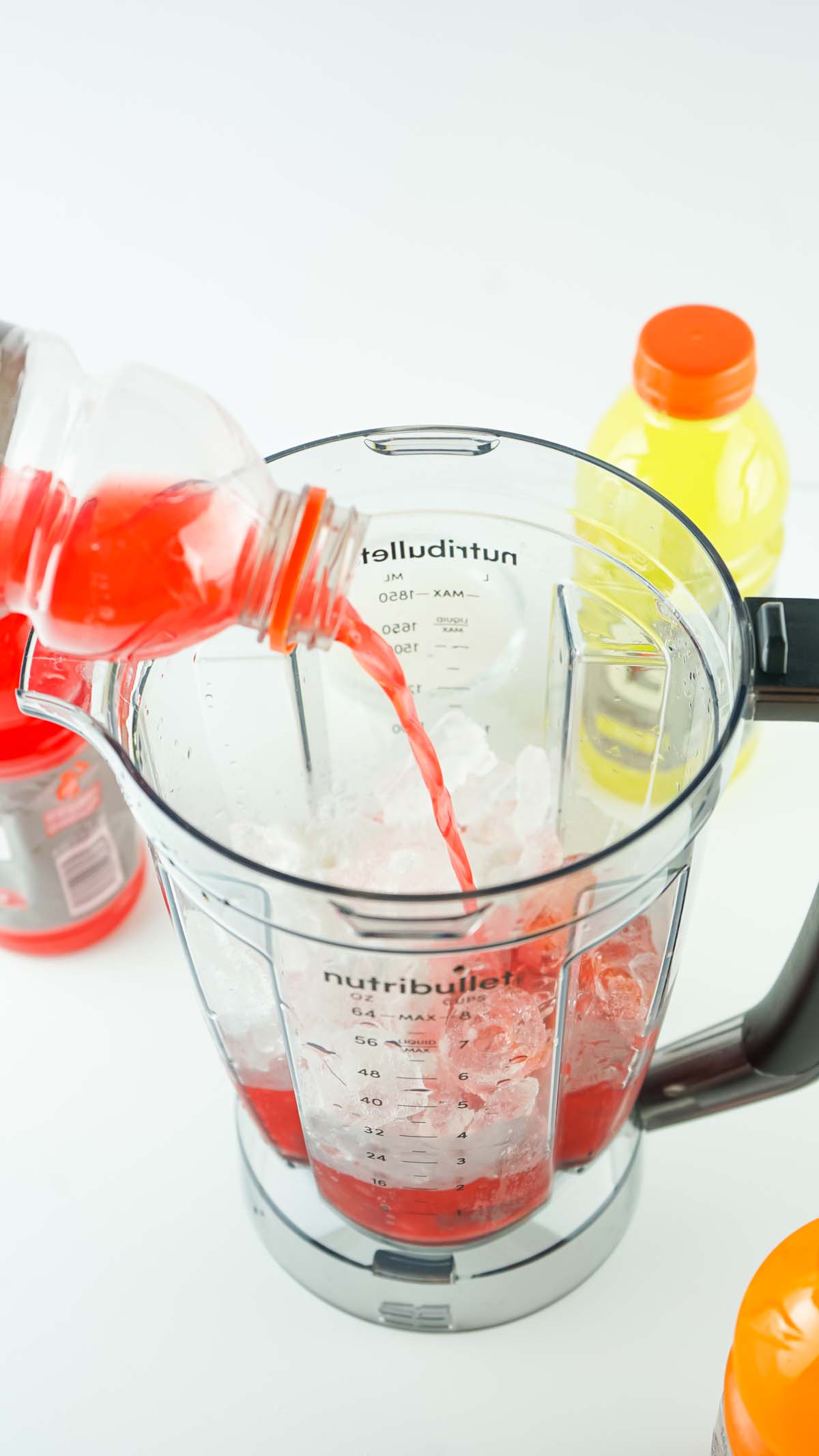 Red Gatorade being poured into the blender with ice.