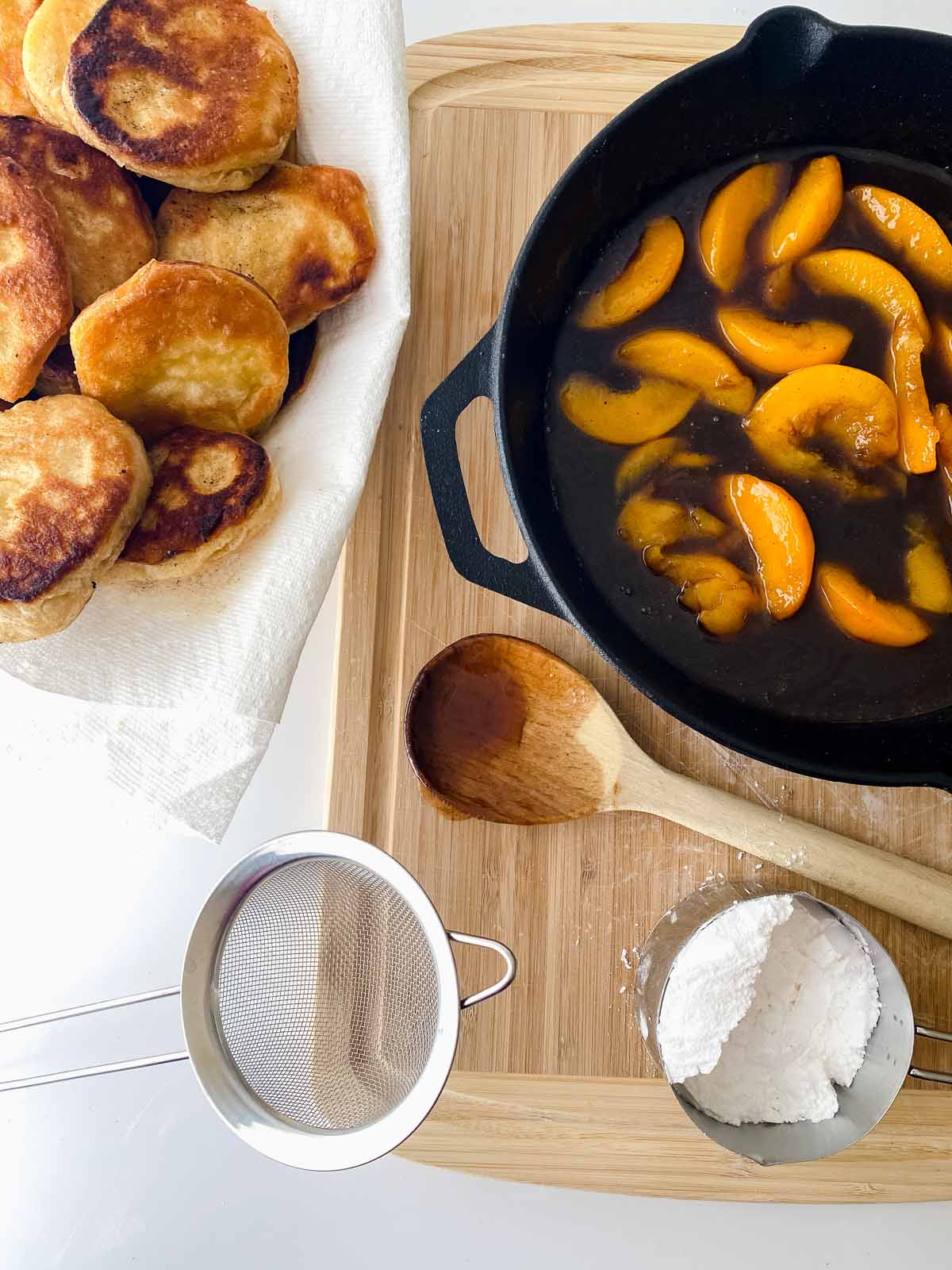 Fried biscuits next to the skillet with peaches.