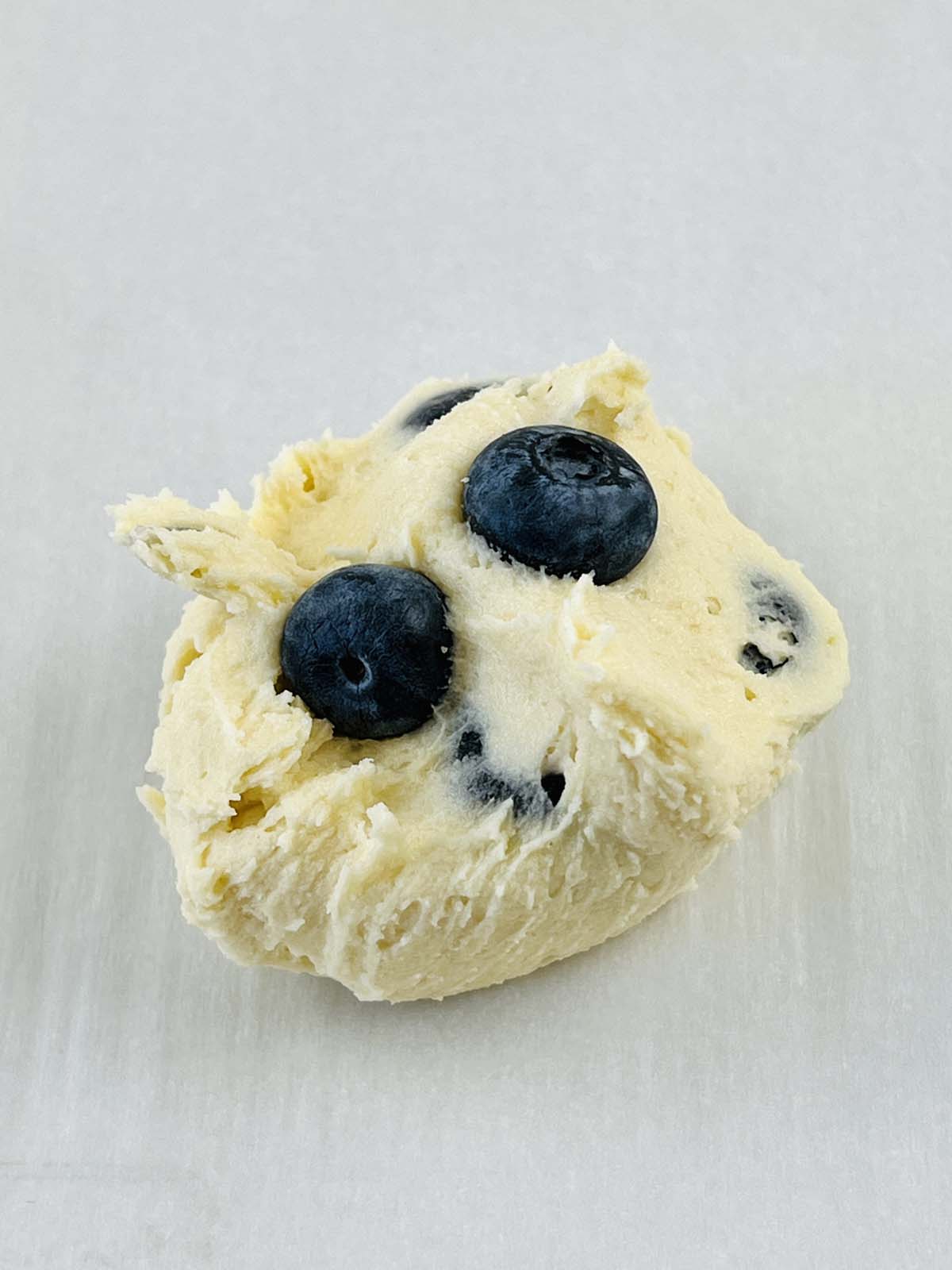 A scoop of cookie dough with blueberries on top.