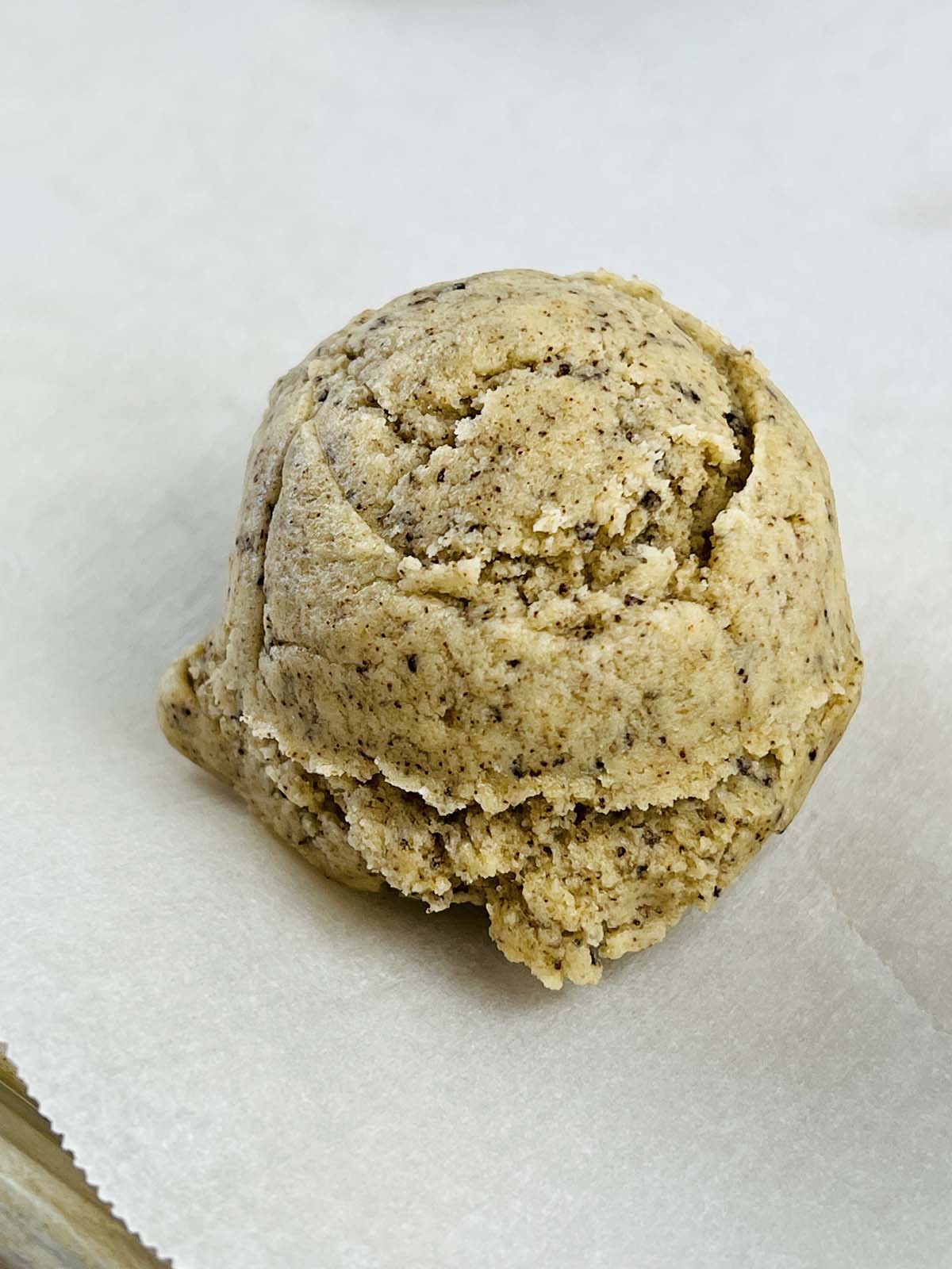 A scoop of cookie dough on parchment paper.