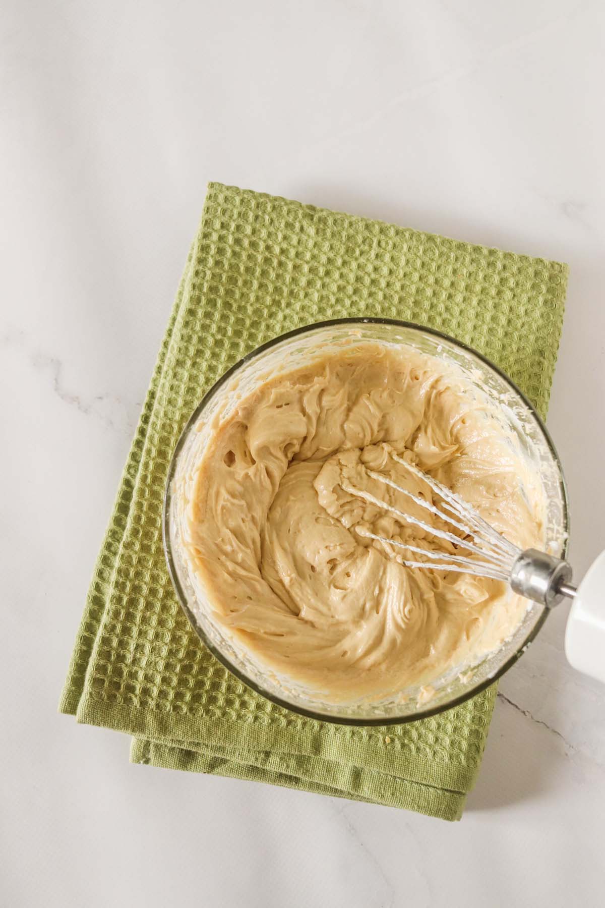Whipped peanut butter in a mixing bowl with a whisk.