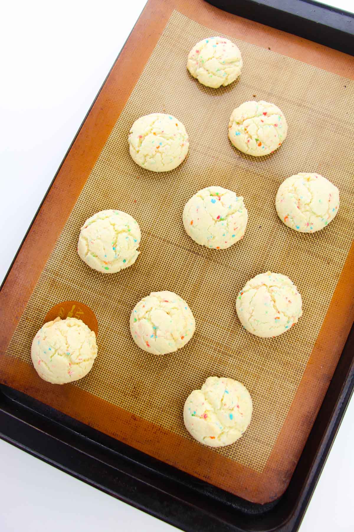 Cookies on a baking sheet lined with a silicone mat.