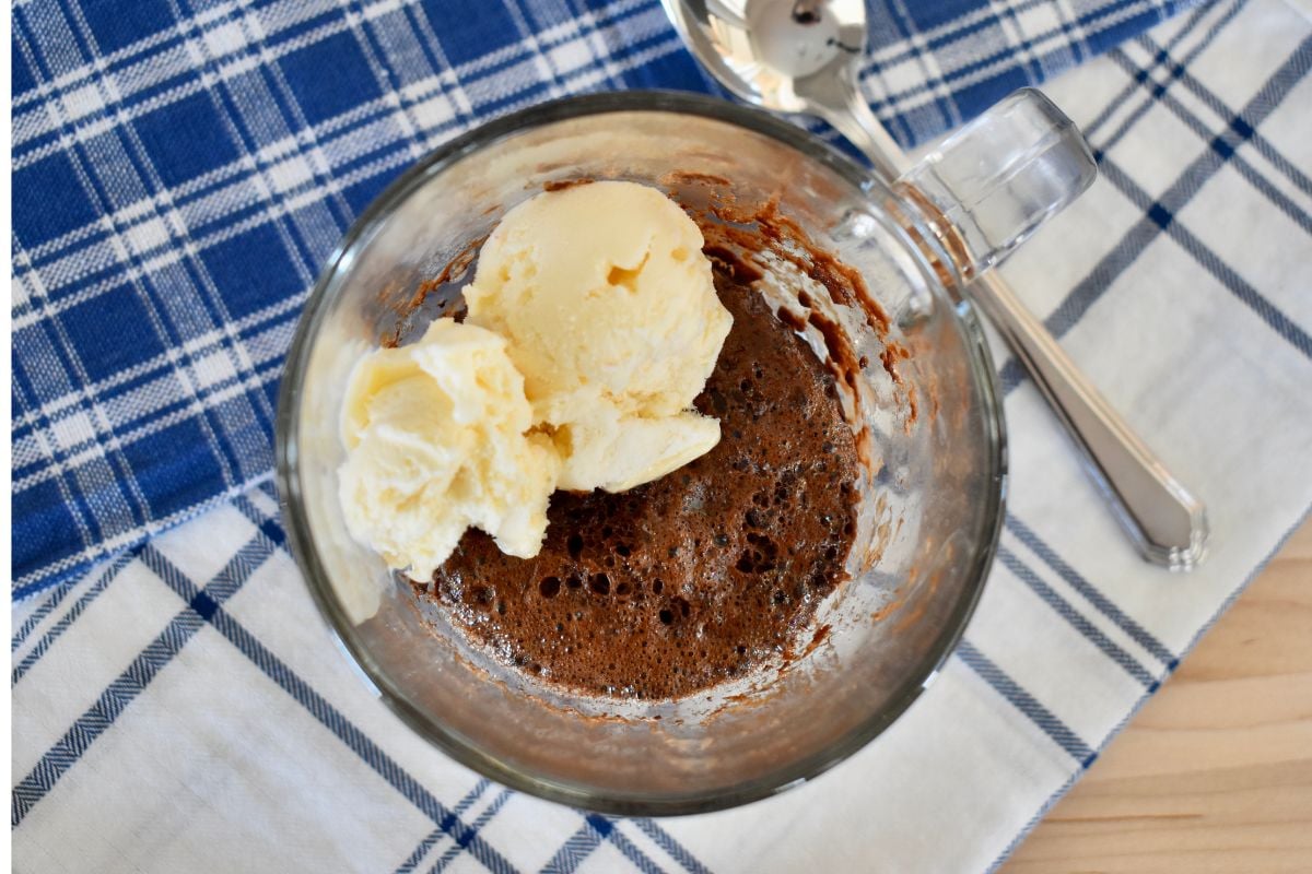 3 ingredient chocolate mug cake in a glass mug with vanilla ice cream on top. 