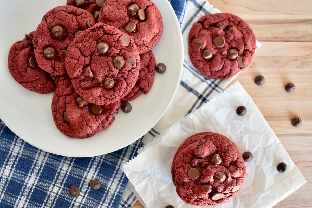 Red velvet cake mix cookies with chocolate chips on a countertop with blue napkins underneath. 