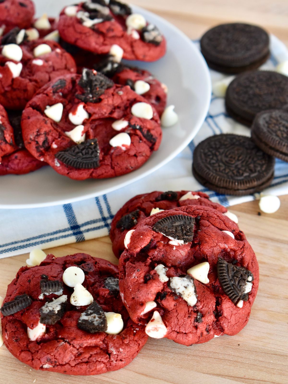 Red velvet Oreo cookies with white chocolate chips stacked on a countertop. 