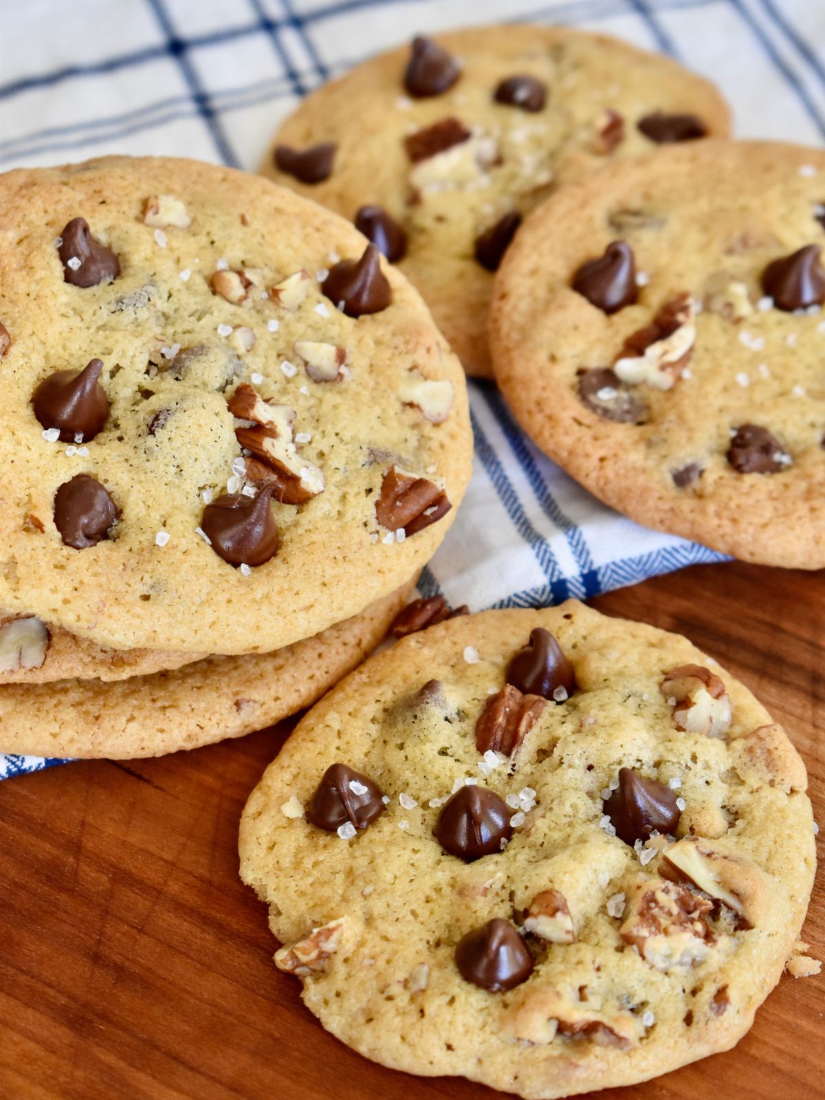 Chocolate Chip Pecan Cookies on a board with chocolate chips and pecans on top. 