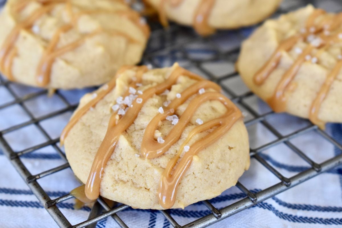Dulce de Leche cookies on a wire rack with dulce de leche drizzled over them.