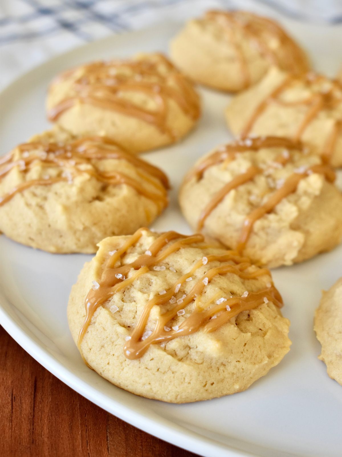 Dulce de Leche cookies on a white plate with dulce de leche drizzled over top of them. 