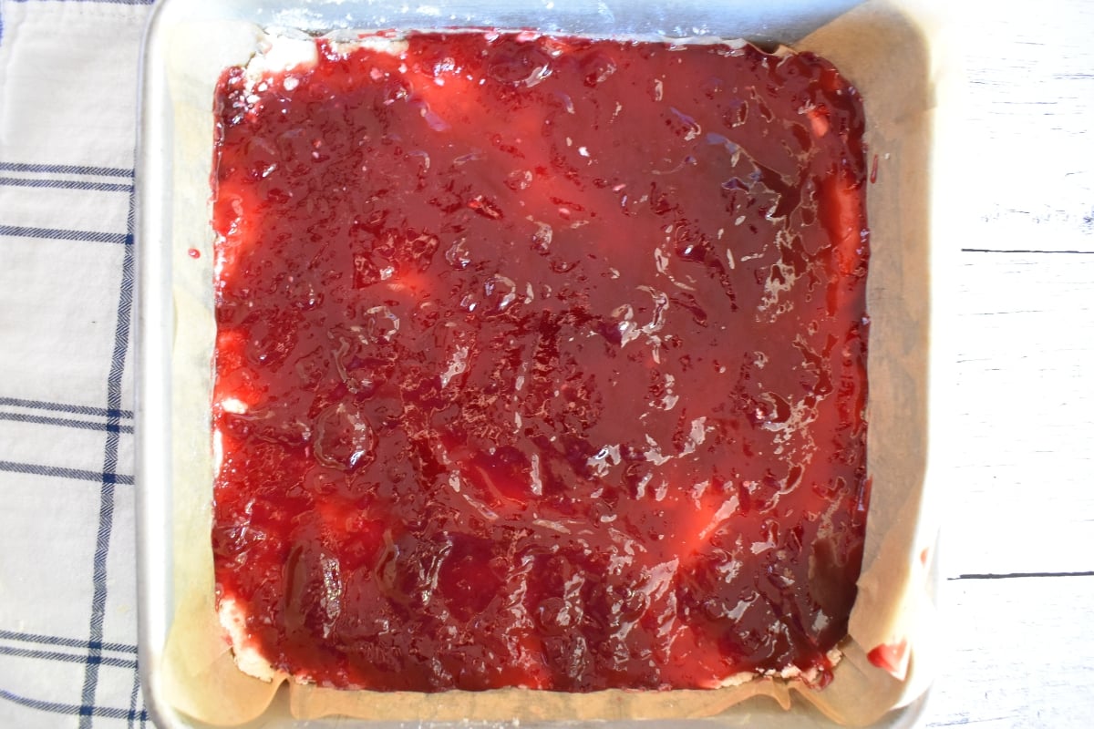 Raspberry jam spread over the shortbread layer.