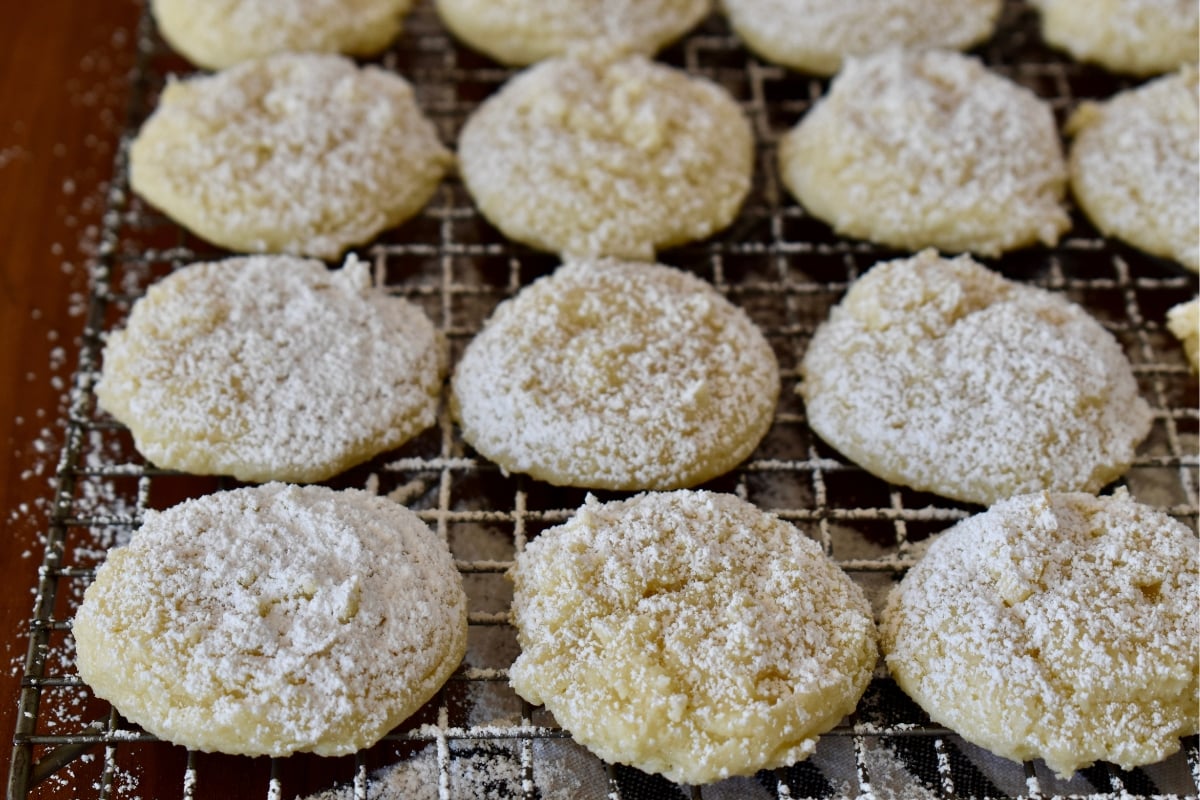 Cream Cheese cake mix cookies on a wire rack with powdered sugar sprinkled on top.