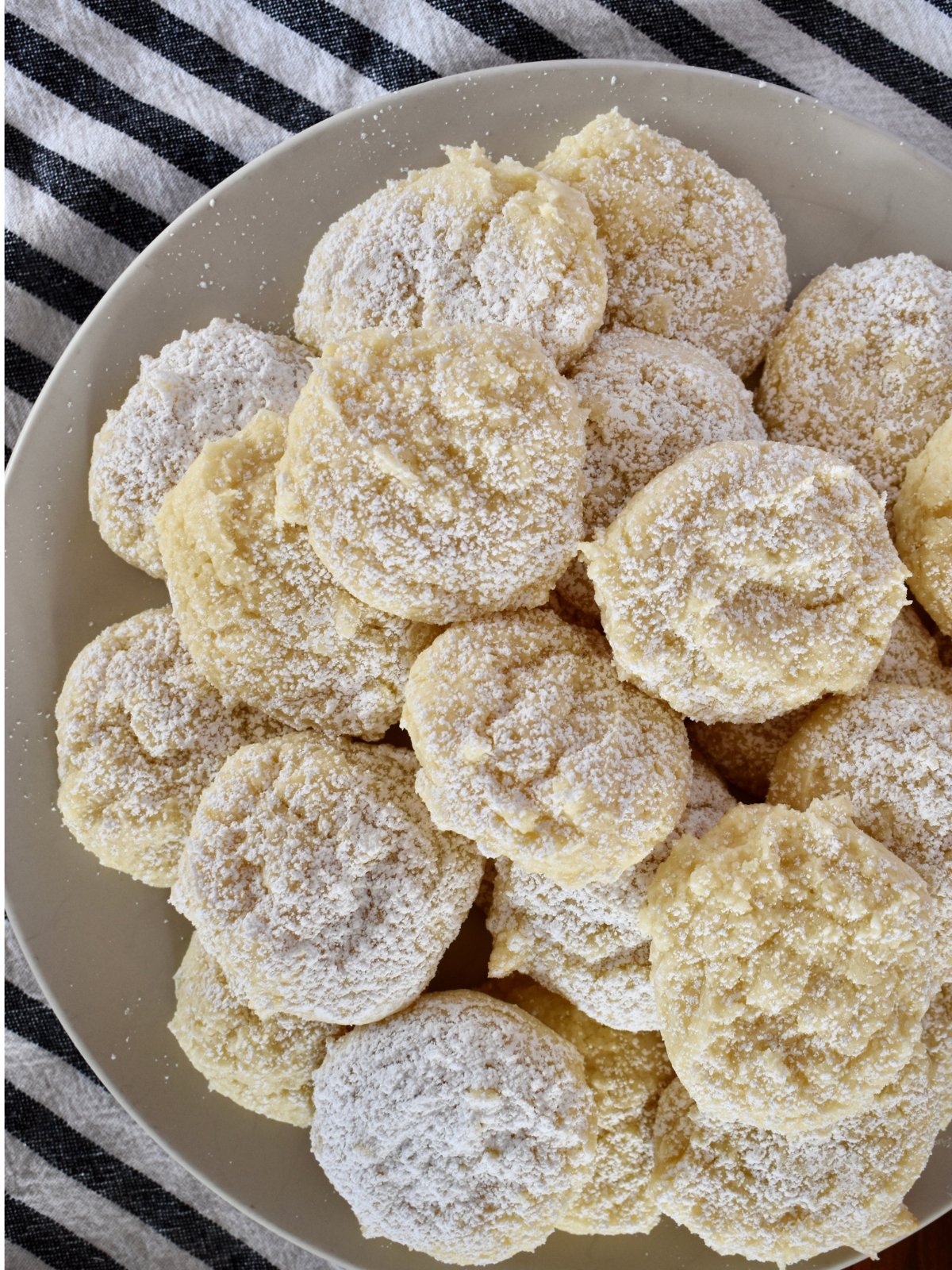 Cream cheese cake mix cookies on a plate with powdered sugar on top.