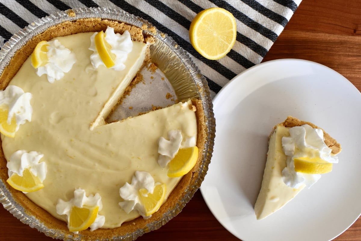 No Bake Lemon Pie with Graham Cracker Crust with a slice of the pie on a white plate. 