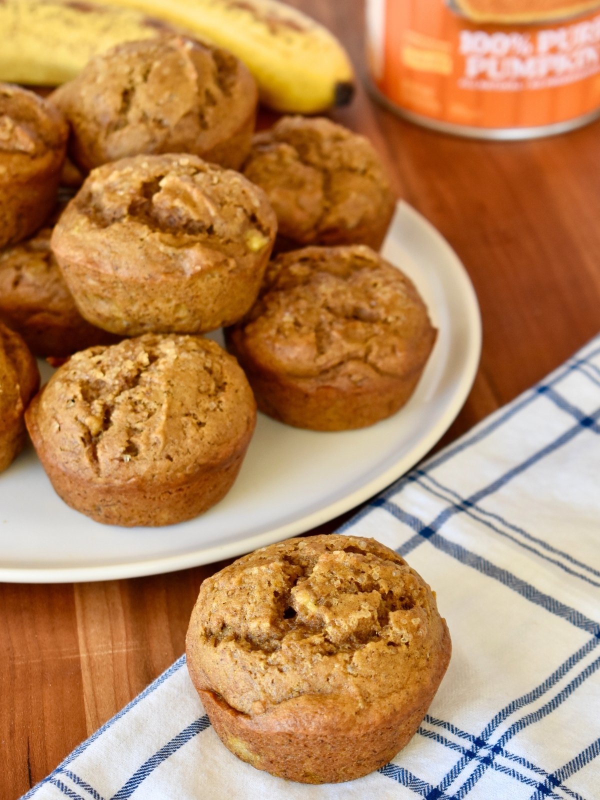 Pumpkin Banana Muffins on a white plate with canned pumpkin and a ripe banana next to it.