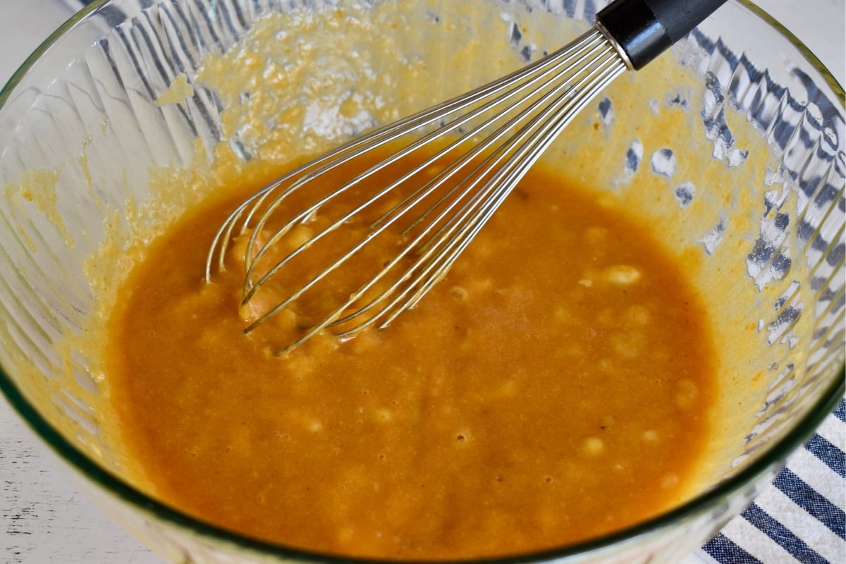 Batter ingredients in a glass bowl with a whisk.